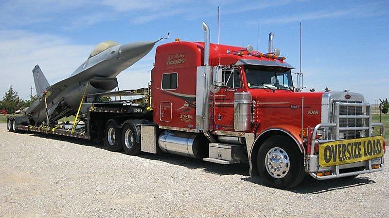 Jet being tied down with 4 inch winch straps on a flatbed trailer