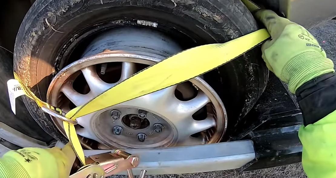 Tow truck using axle straps to secure