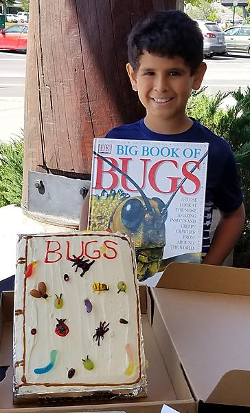 Boy with book about bugs and cake with bugs