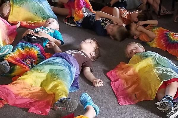 children under tiedye scarves at music school program