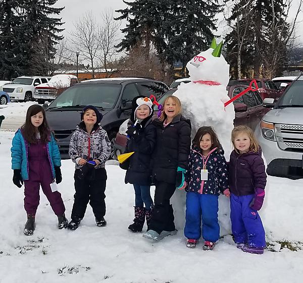 kids in front of a big snowman