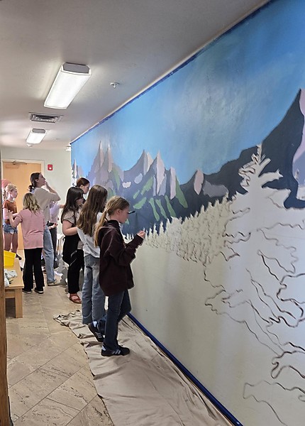 Students paint library wall under direction of artist