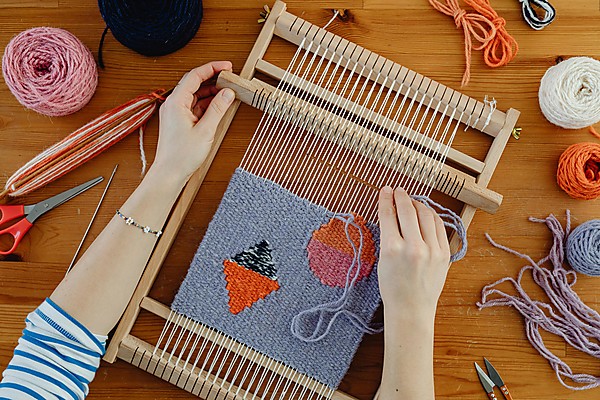 person weaving on a lap loom